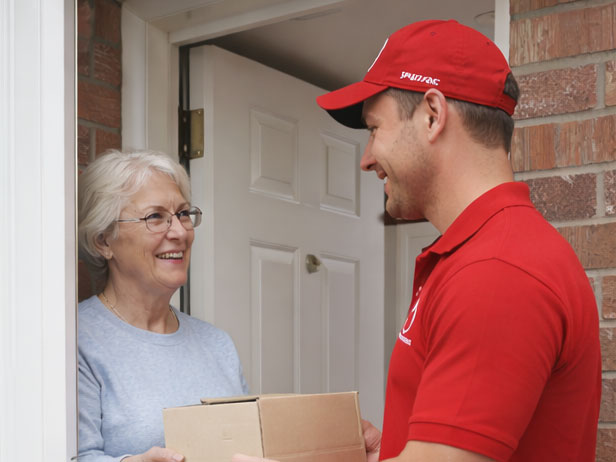 Delivery agent handing a parcel to an elderly woman